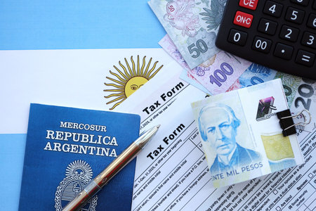 Argentine pesos money bills in big amount lies on table with pen, calculator, passport and tax forms close up. Finance and banking conceptの写真素材
