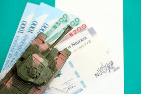 Nigerian naira currency money bills and toy tank on flag close up.の写真素材