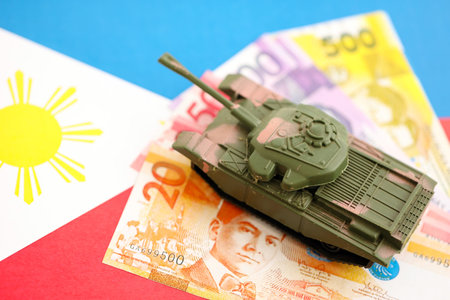 Philippines peso currency money bills and toy tank on flag close up.の写真素材