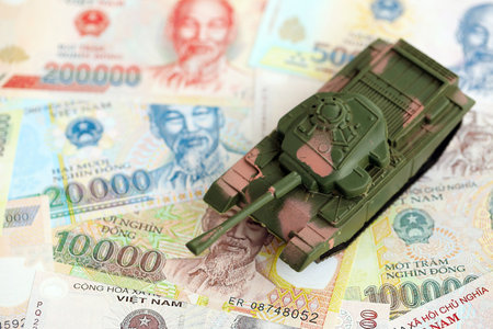 Vietnamese dong currency money bills and toy tank close up. The concept of army funds and weapons salesの写真素材