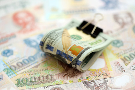 Vietnamese dong currency money bills and bunch of us dollar banknotes close up. The concept of...