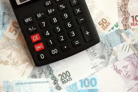 Brazilian reais banknotes and calculator. The current Brazil real money bills and calculator lies on table in big amount. The concept of taxation and money count in Brazilの写真素材