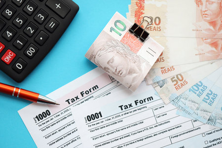 Brazilian reais banknotes with calculator and tax form. The current Brazil real money bills and tax blank close up. The concept taxpaying and accounting in Brazilの写真素材