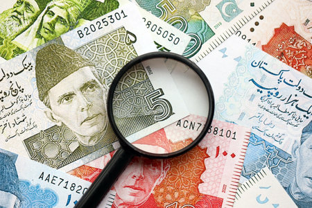 Pakistan rupees banknotes and magnifying glass. The current Pakistan money bills and magnifying glass lies on table in big amount. The concept of financial monitoring and taxation in Pakistanの写真素材