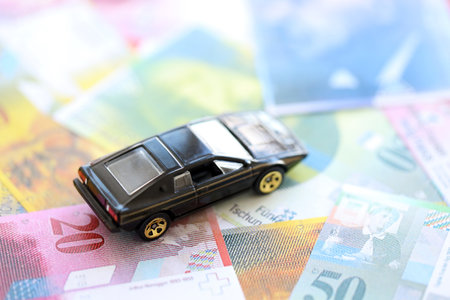 Swiss franc banknotes and toy car. The current francs money bills and black car lies on table in big amount. The concept of car ownership in Switzerlandの写真素材