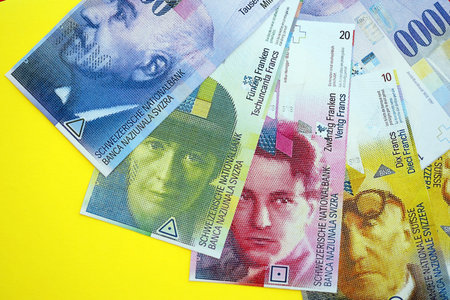 Swiss franc banknotes on yellow. The current francs money bills lies on table in big amount. The...