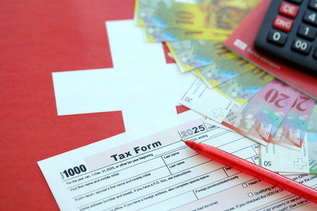 Swiss franc banknotes and tax form on flag. The current francs money bills lies on tax form and flag. The concept of taxation in Switzerlandの写真素材