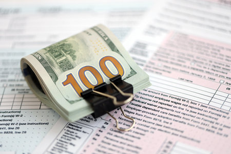 Big amount of United States USD dollar bills on table with 1040 individual income tax return form....