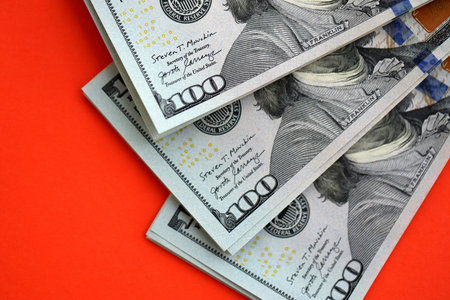 Big amount of United States hundred dollar bills on red background. Concept of taxation and money...