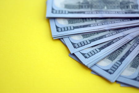 Big amount of United States hundred dollar bills on yellow background. Concept of taxation and money making in United Statesの写真素材