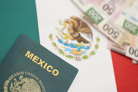 Mexican pesos money bills in big amount and passport lies on Mexico flag close up. Finance and banking conceptの写真素材
