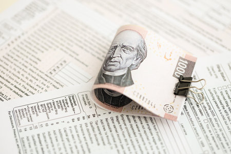 Mexican pesos money bills in big amount lies on table with tax forms close up. Accounting and taxation conceptの写真素材