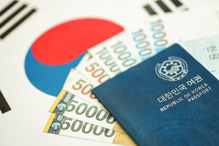 South Korean won money bills in big amount and passport lies on South Korea flag close up. Finance and banking conceptの写真素材