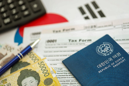 South Korean won money bills in big amount lies on table with pen, calculator, passport and tax forms close up. Taxpaying and accounting conceptの写真素材