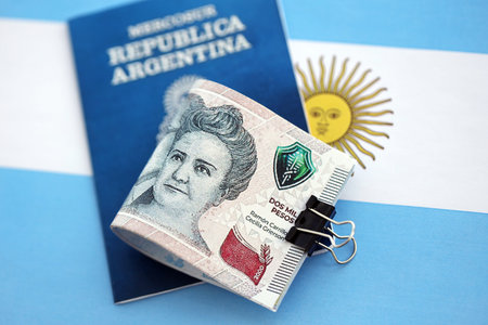 Argentine pesos money bills in big amount and passport lies on Argentina flag close up. Finance and banking conceptの写真素材