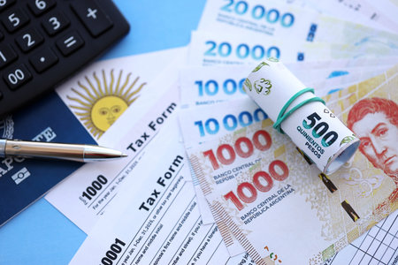 Argentine pesos money bills in big amount lies on table with pen, calculator, passport and tax forms close up. Finance and banking conceptの写真素材
