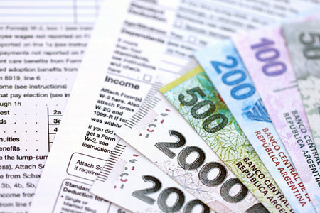 Argentine pesos money bills in big amount lies on table with pen and tax forms close up. Finance and banking conceptの写真素材
