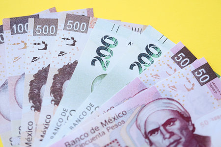 Mexican pesos money bills in big amount lies on yellow color table close up. Finance and banking conceptの写真素材