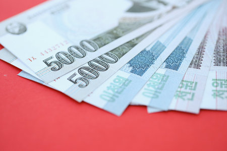 North Korean won money bills in big amount lies on red color table close up. Finance and banking...