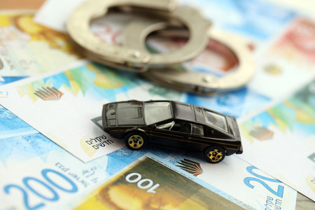 Israel New Shekels banknotes and toy car with handcuffs. The current Israel money bills and black...