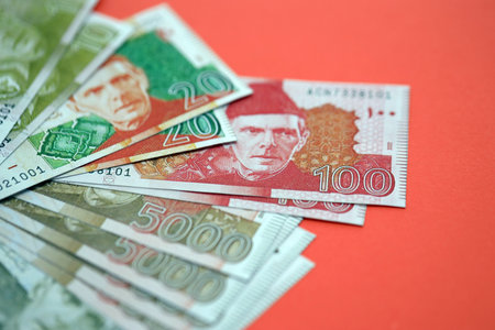 Pakistan rupees banknotes on red background. The current Pakistan money bills lies on table in big...