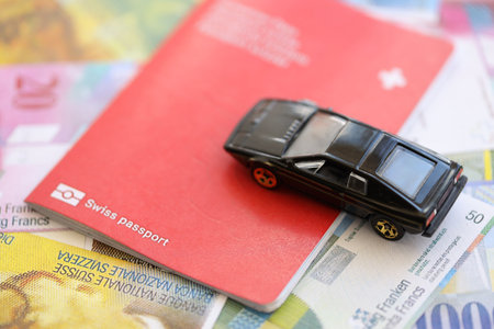 Swiss franc banknotes and toy car with passport. The current francs money bills and black car with pass lies on table in big amount. The concept of car ownership in Switzerlandの写真素材