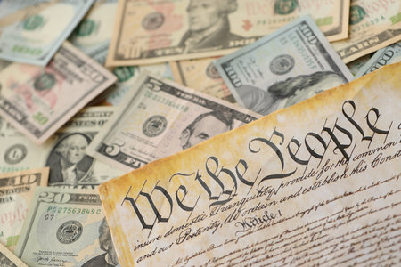 American US dollars money bills with coins and constitution close up on american flag. The American...