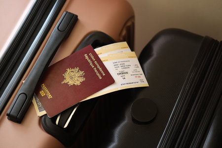 French passport with tickets lies on touristic suitcase close up in airport waiting hall. Travel worldwide and international tourism conceptの写真素材