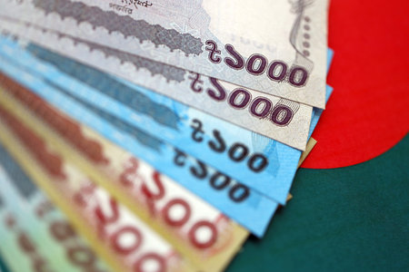 Bangladeshi taka money bills in big amount lies on Bangladesh flag close up. Finance and banking...
