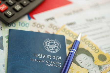 South Korean won money bills in big amount lies on table with pen, calculator, passport and tax forms close up. Taxpaying and accounting conceptの写真素材