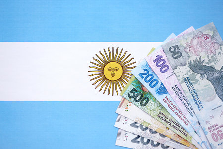 Argentine pesos money bills in big amount lies on Argentina flag close up. Finance and banking conceptの写真素材