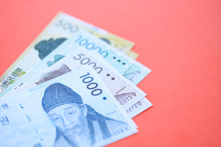South Korean won money bills in big amount lies on red color table close up. Finance and banking...