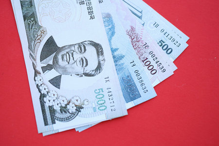 North Korean won money bills in big amount lies on red color table close up. Finance and banking conceptの写真素材