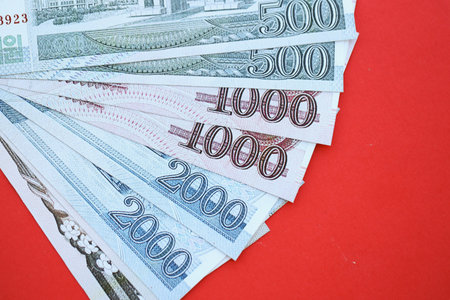 North Korean won money bills in big amount lies on red color table close up. Finance and banking conceptの写真素材