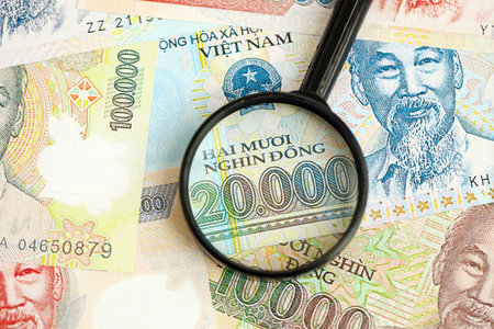 Vietnamese dong currency money bills and magnifying glass close up. The concept of financial monitoring and taxationの写真素材