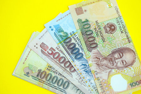 Vietnamese dong money bills in big amount close up on yellow. Finance and banking concept