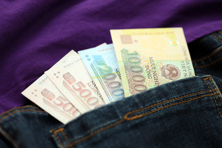 Vietnamese dong money bills in denims pocket close up. The concept of fashion and wealthの写真素材