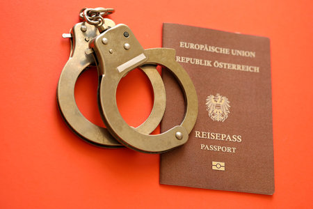 Austria passport with police handcuffs on table close up.の写真素材