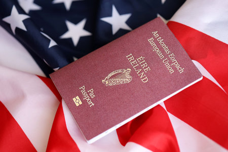 Ireland passport on big waving flag of United States of America close up.の写真素材