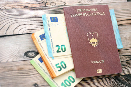 Slovenia passport lies with euro money banknotes on wooden background close up. Cash and payments in...