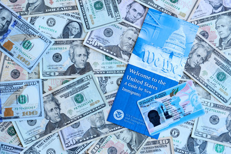 Permanent resident green card and guide for new immigrants lies on many dollar bills close upの写真素材