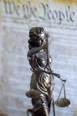 Lady Justice bronze statue and US Constitution blurred page close up. Lawsuit and justice in United...