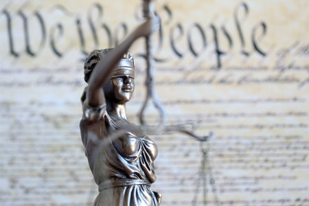 Lady Justice old statue and US Constitution blurred page close up. Lawsuit and justice in United States of Americaの写真素材