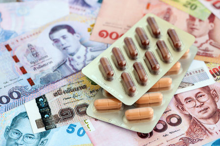 Thai baht currency money bills and medicine pills close up. The concept of medicine and pharmacyの写真素材