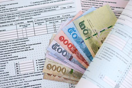 Thai baht money bills on tax form close up. Taxation and accounting conceptの写真素材