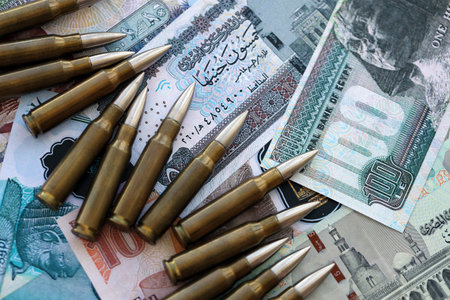 Egyptian pound currency money bills and rifle bullets close up.