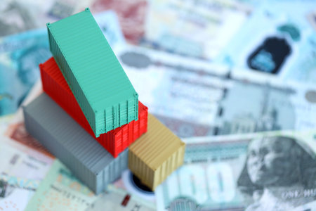 Egyptian pound currency money bills and toy cargo containers close up. The concept of shipping and...