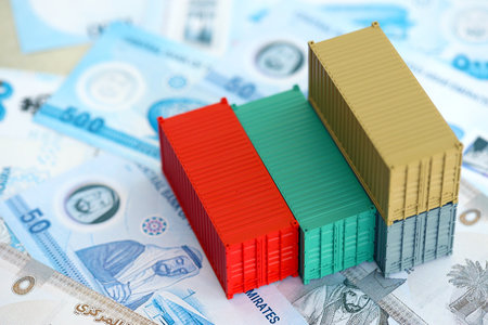 United Arab Emirates dirham currency money bills and toy cargo containers close up. The concept of...
