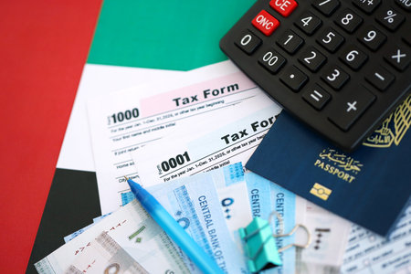 United Arab Emirates dirham money bills and calculator with tax form on flag close up. Taxation and accounting conceptの写真素材