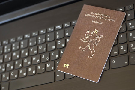 Luxembourg passport lies on black laptop keyboard buttons background close up. Technologies and control in Europe conceptの写真素材